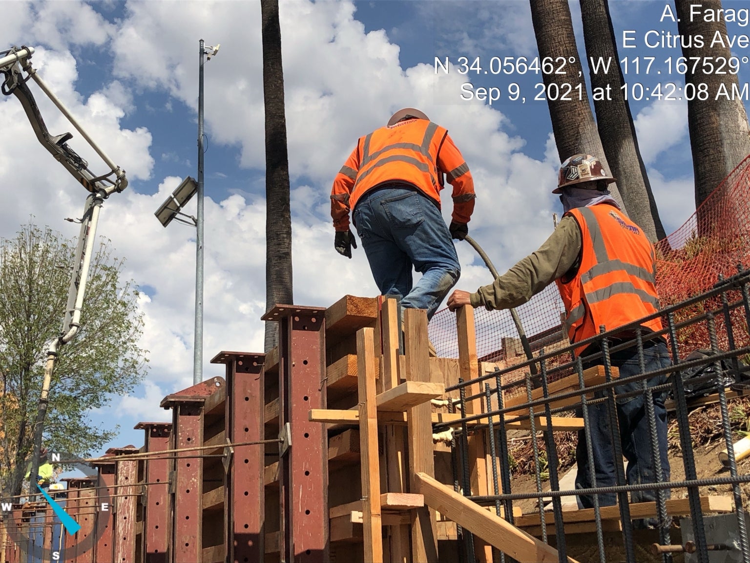 A group of men in orange vests standing on a wooden beam.