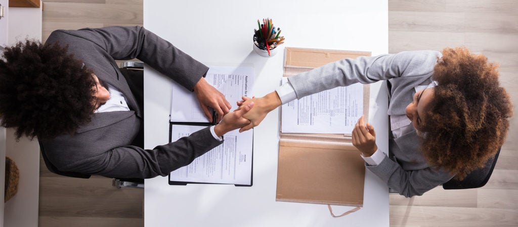 Photo of a man and woman shaking hands across a table