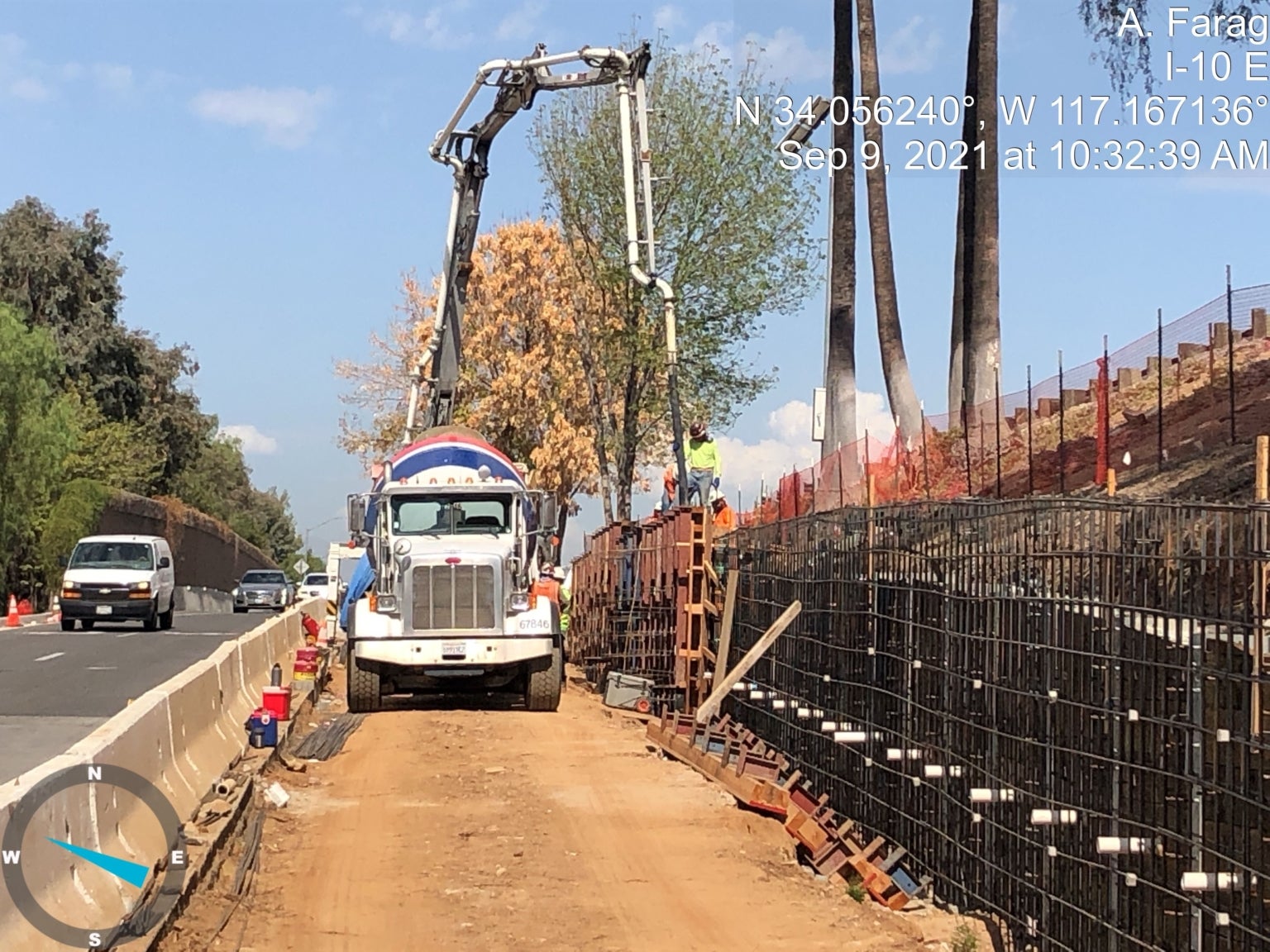 A concrete mixer truck and a pump truck are on a construction site, pouring concrete into formwork beside a road under clear skies.