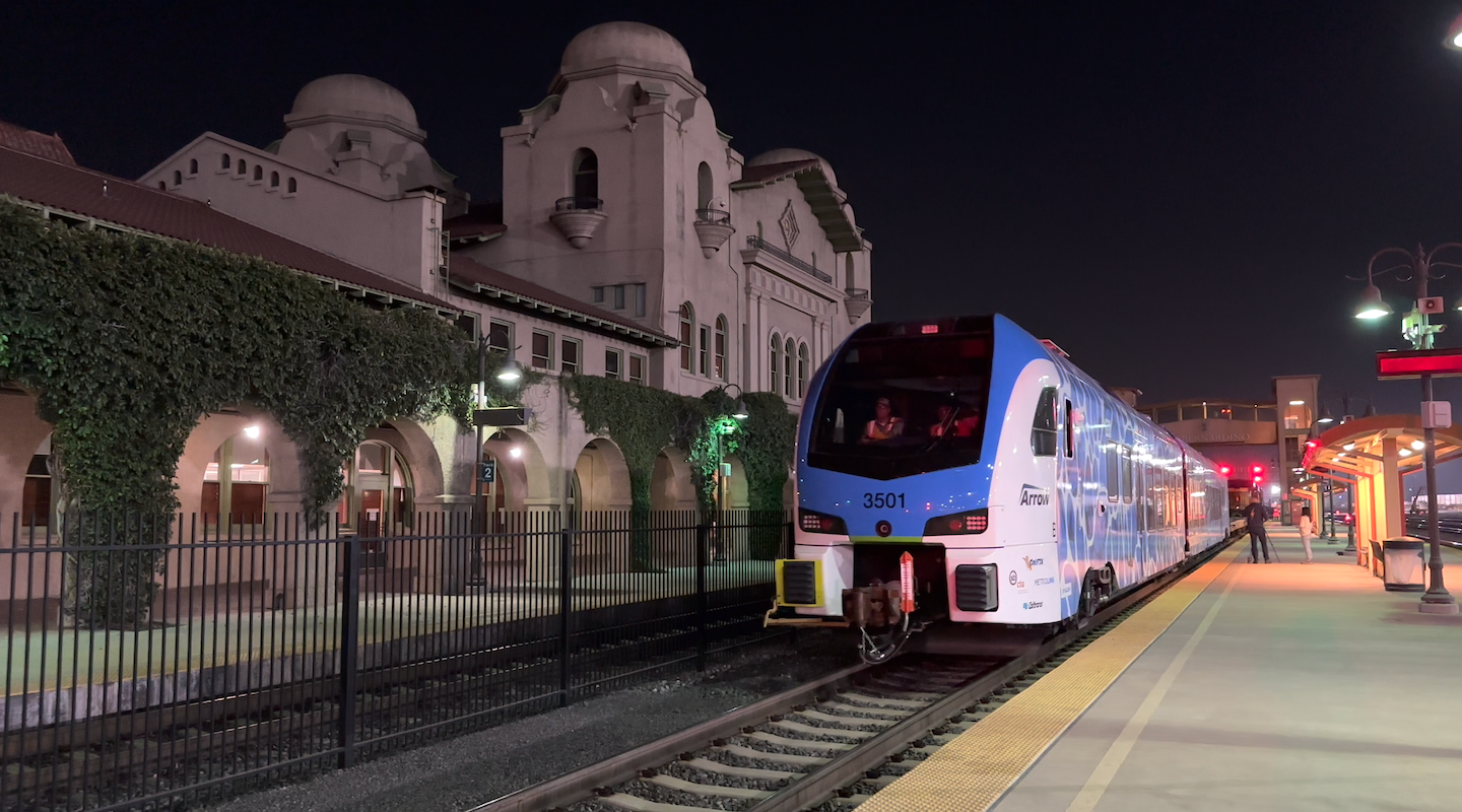 A modern blue and white passenger train numbered 3501 is stopped at a well-lit station platform at night.